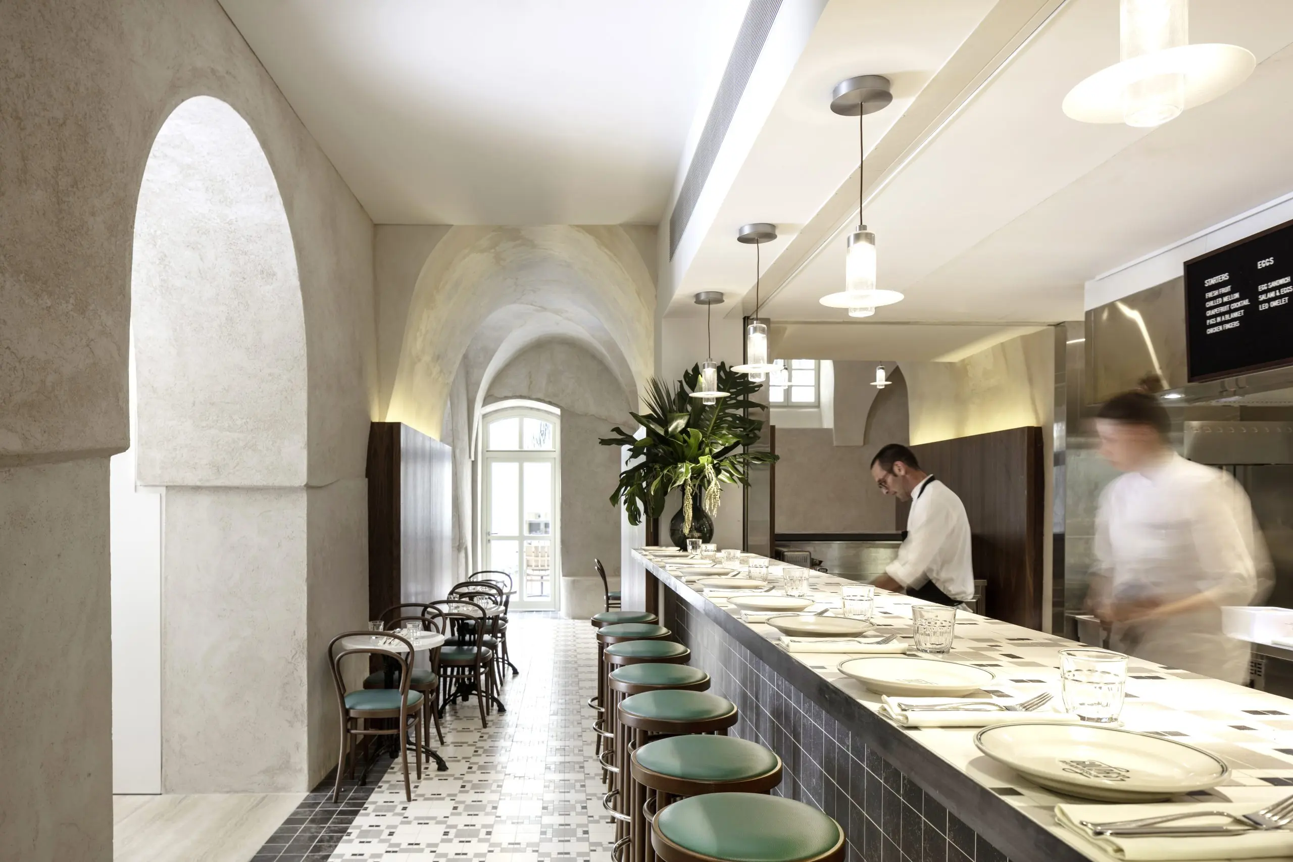 Restaurant mit langer Theke, offener Küche und Gewölbedecke