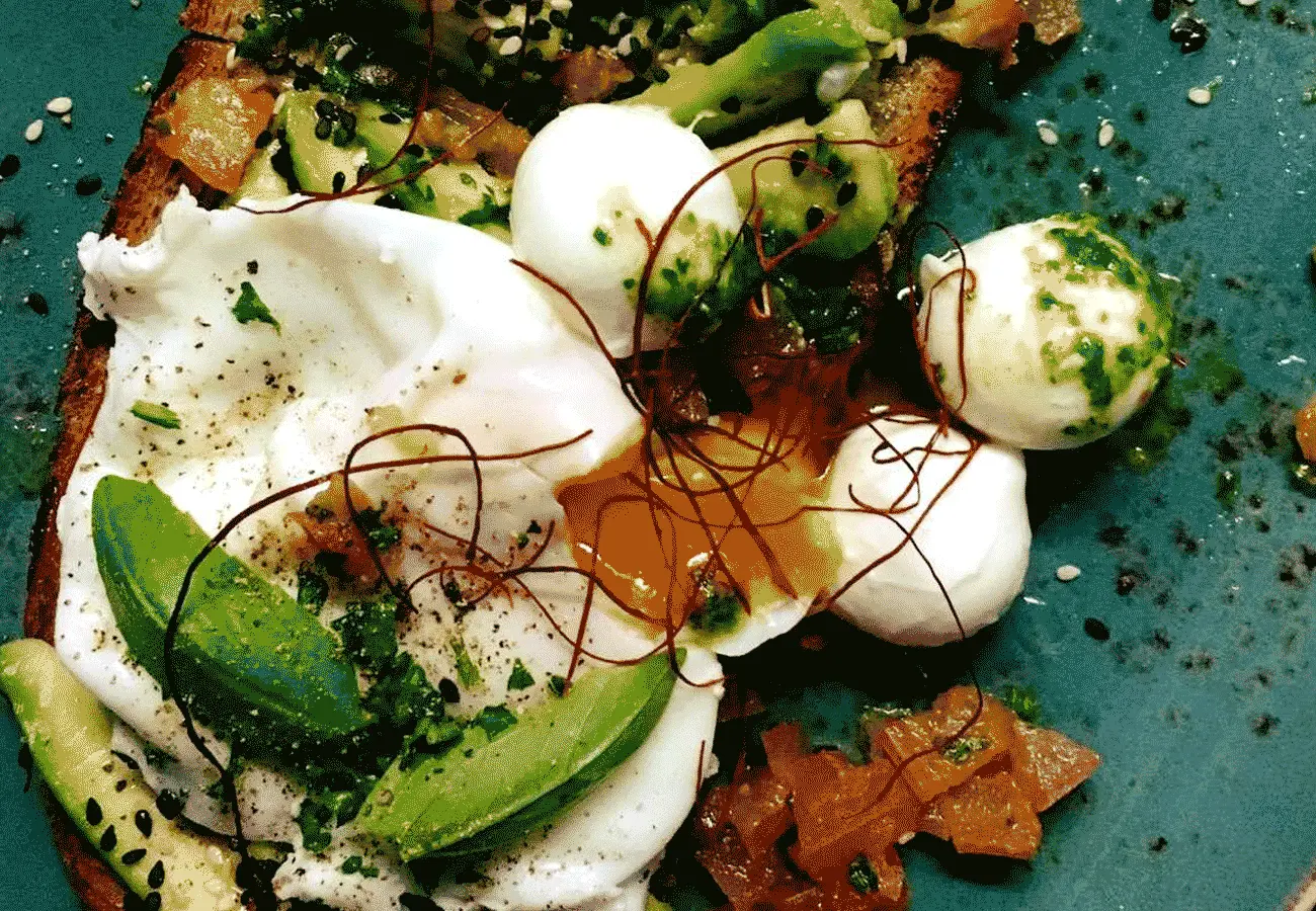 Angerichteter Teller mit pochierten Eiern, Avocado und Mozzarella