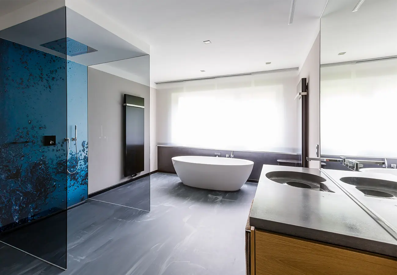 Badezimmer mit freistehender Wanne und blau gestalteter Glaswand